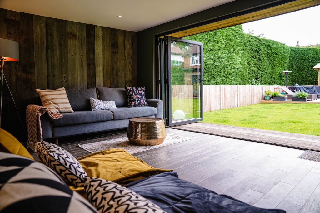 Inside of a room with sofa and pillows looking into a green garden