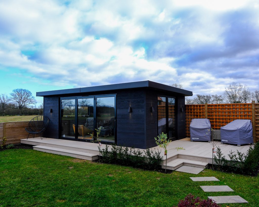 Small black rectangular wooden building in a garden
