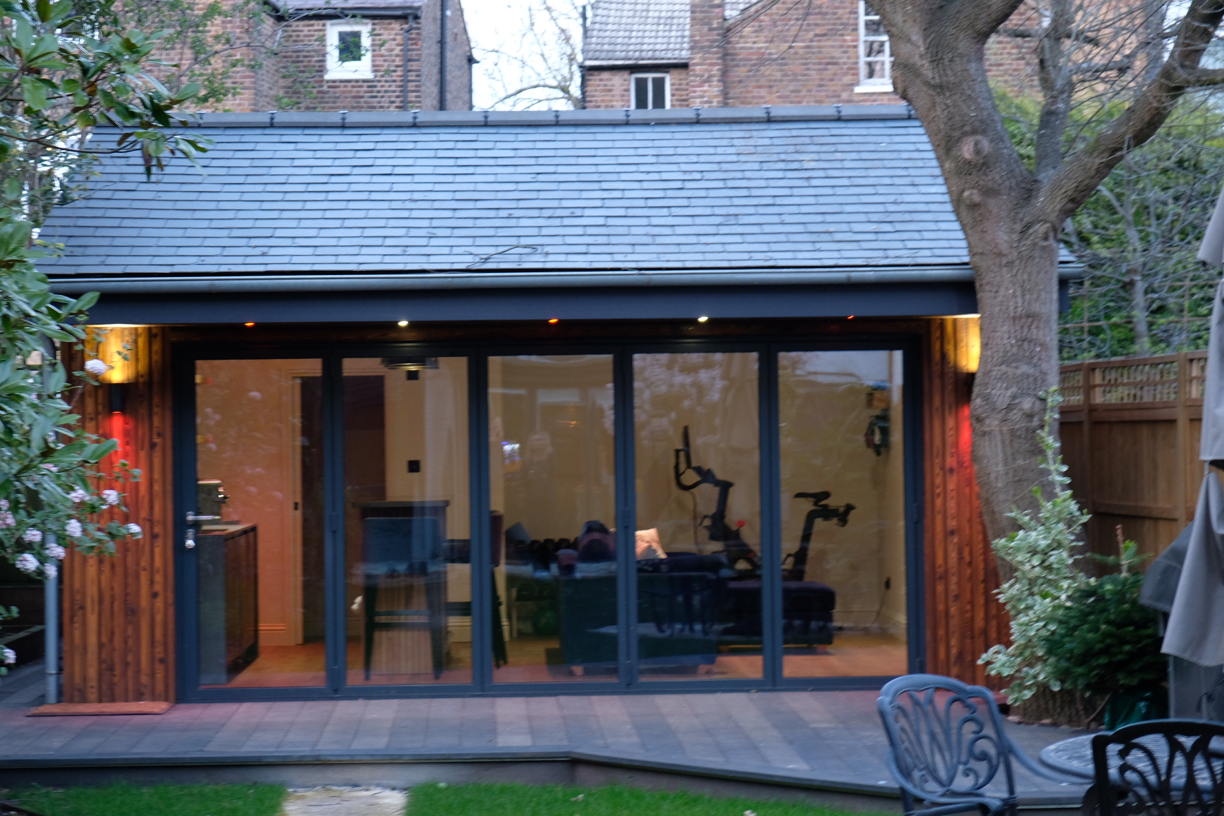 Bespoke garden building illuminated at dusk by Into The Garden Room